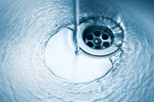 Kitchen sink with water falling down drain.