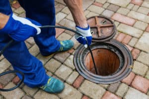 Sewer cleaning service - worker cleans a clogged drain with hydro jetting.