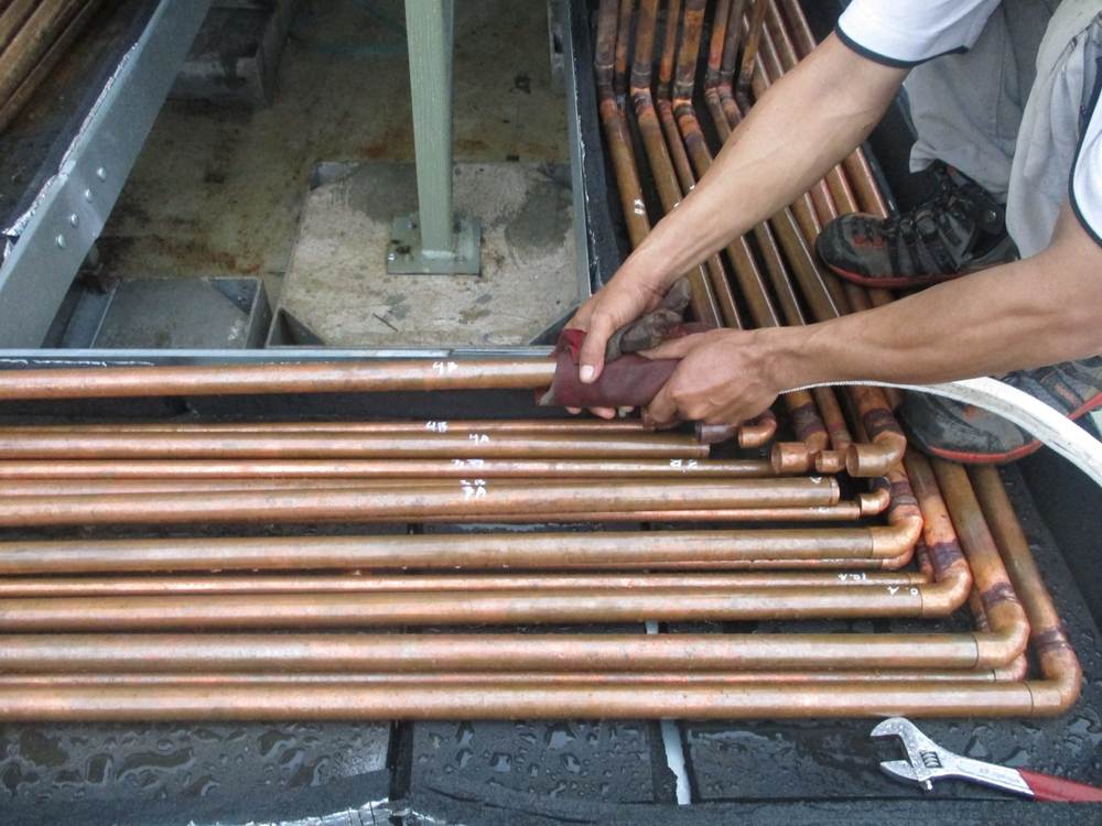 A plumber working with several copper pipes.