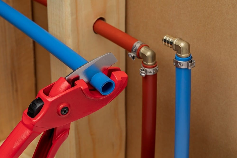 Clippers cutting red and blue PEX pipes.